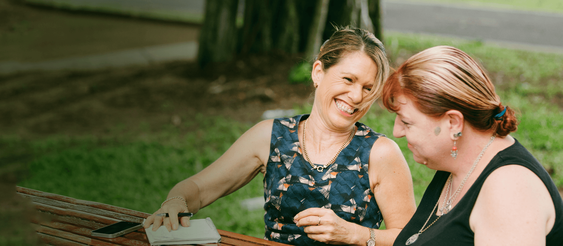 Job seeker and employment consultant sit at a bench outside