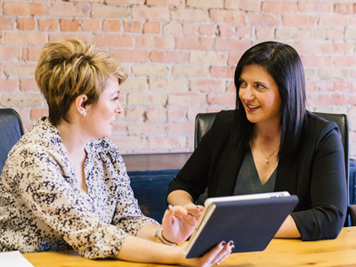 Two CoAct Service Partner staff members holding a discussion while looking at data on an ipad